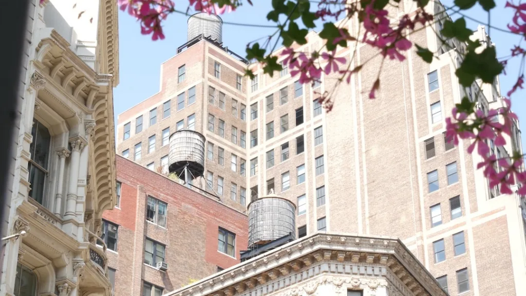 New York City Broadway, Manhattan midtown classic building corner architecture. Urban residential house exterior. Real estate property in USA. Typical brick facade. Rooftop water tower, tank on roof.