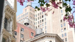 New York City Broadway, Manhattan midtown classic building corner architecture. Urban residential house exterior. Real estate property in USA. Typical brick facade. Rooftop water tower, tank on roof.