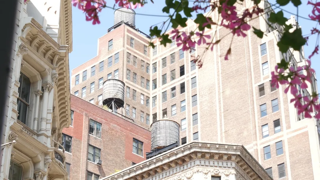 New York City Broadway, Manhattan midtown classic building corner architecture. Urban residential house exterior. Real estate property in USA. Typical brick facade. Rooftop water tower, tank on roof.