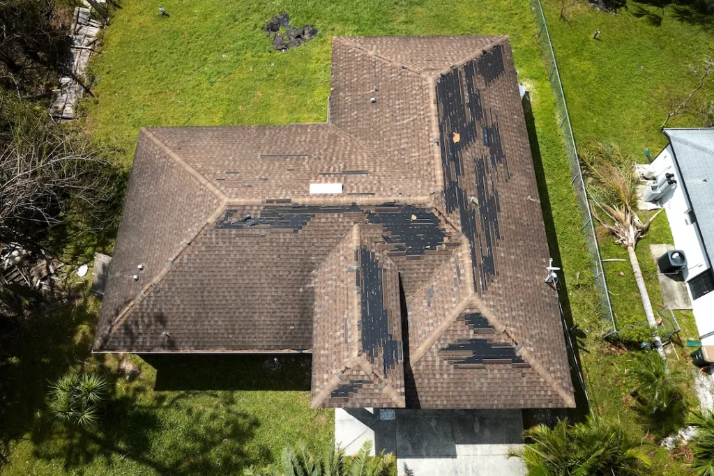 Damaged house roof with missing shingles after hurricane Ian in Florida. Consequences of natural disaster